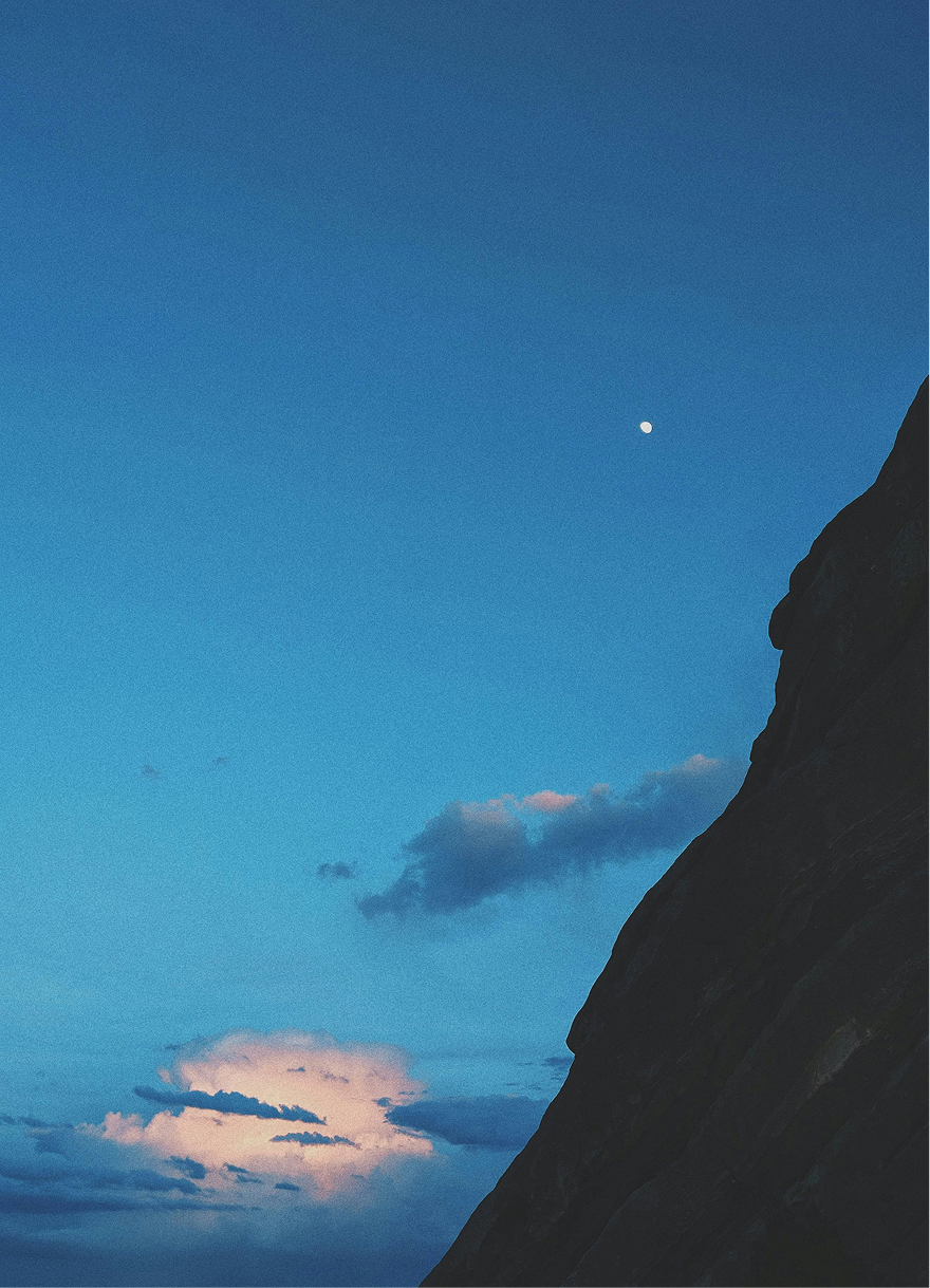 Photograph of the moon next to a mountain